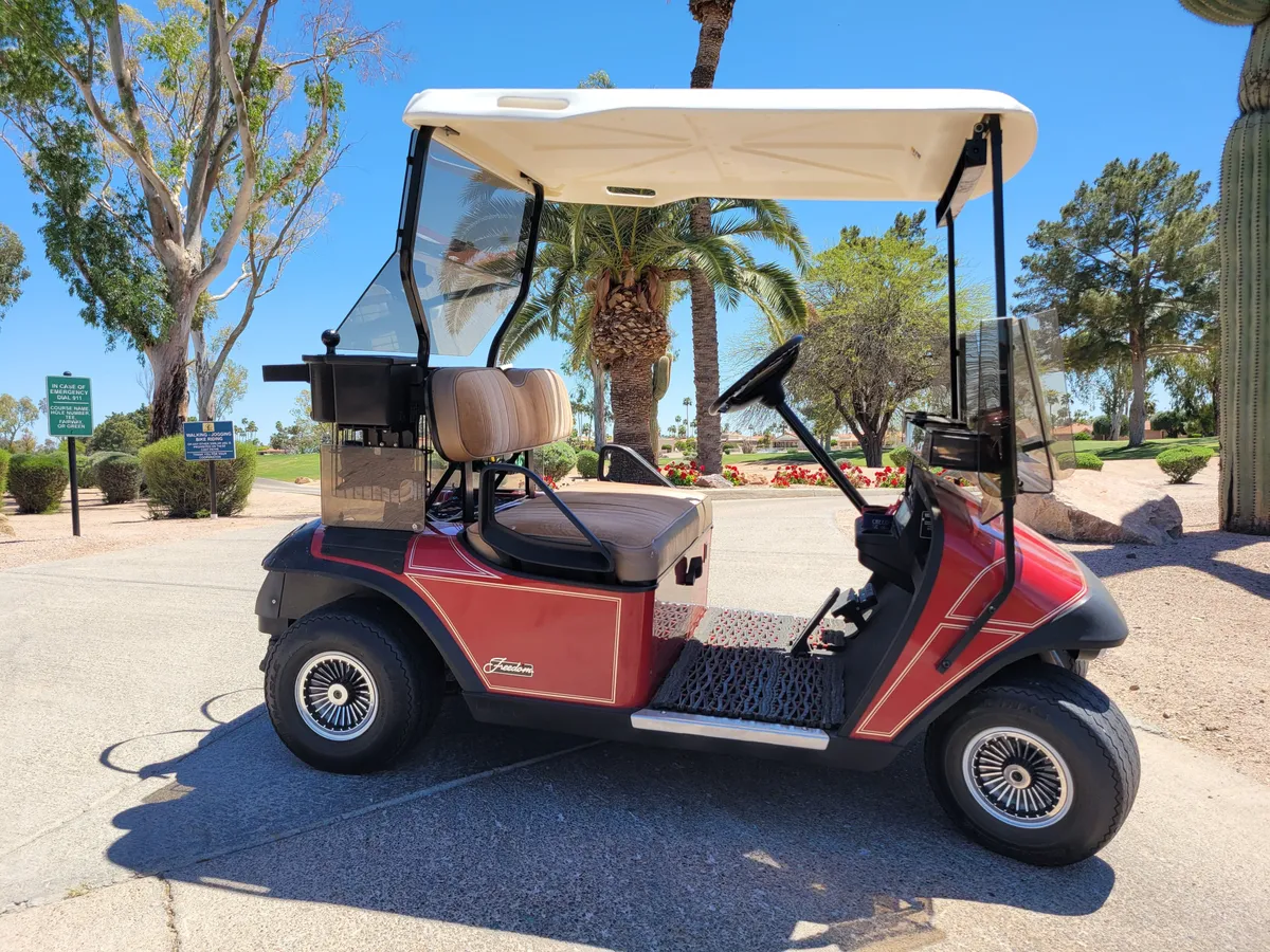 A picturesque landscaped area with palm trees and a golf cart parked beside a path, highlighting the ease of access to the neighborhood's recreation and the convenience of on-site amenities.