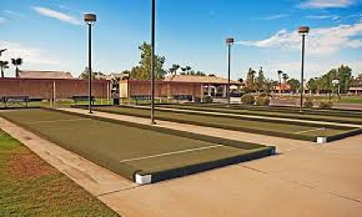 This image features bocce ball courts set within a landscaped exterior, complete with benches for spectators and casual relaxation. The courts are surrounded by greenery and lit by lampposts, conveying a sense of active community life and opportunities for friendly competition or socializing close to home.